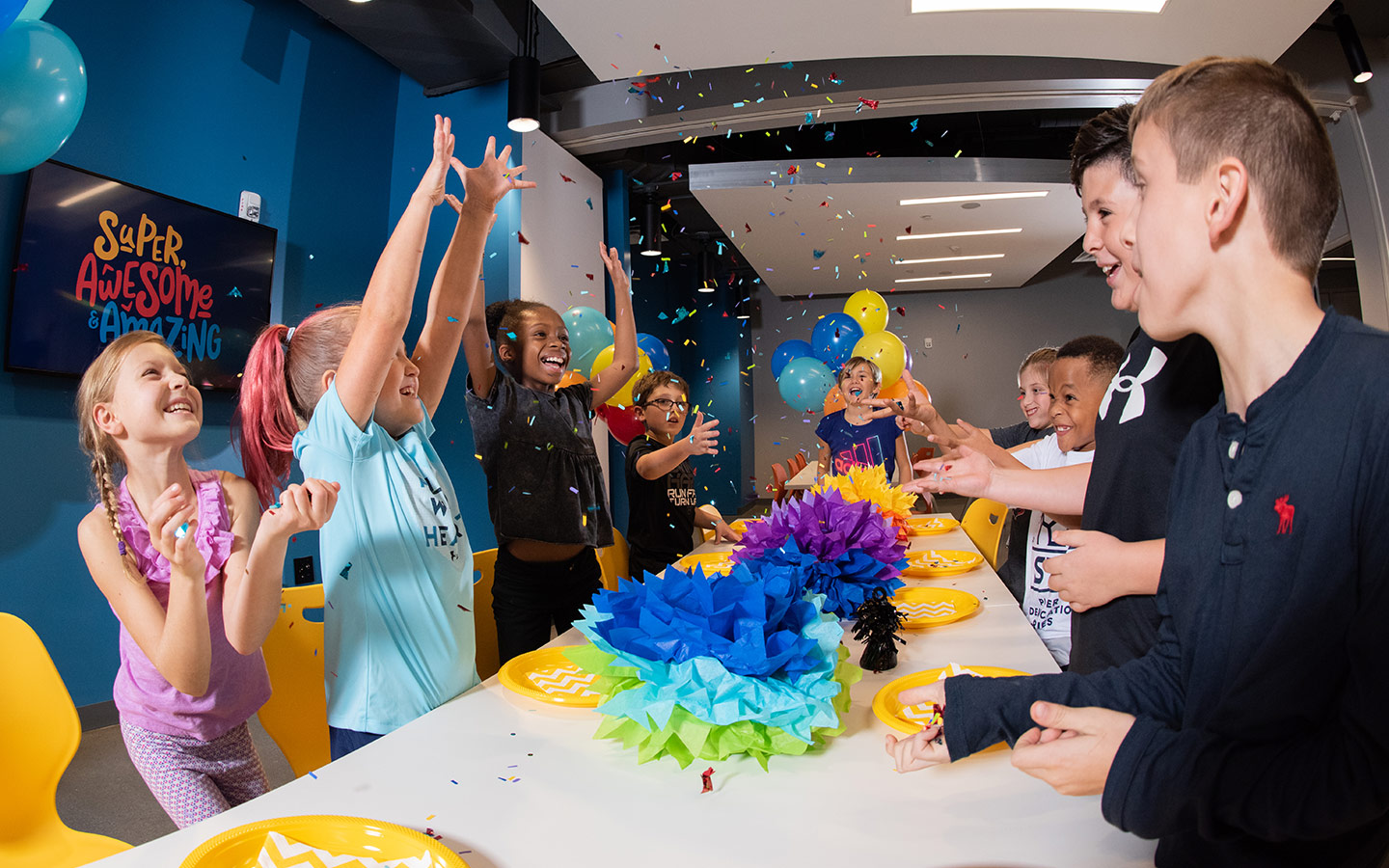 Group of kids celebrating with confetti around a party table