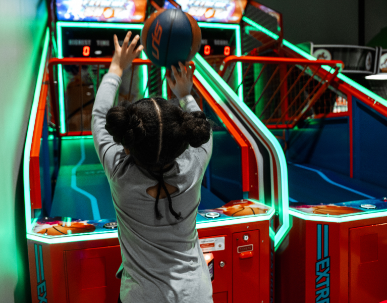 Child shooting basketball as part of arcade game