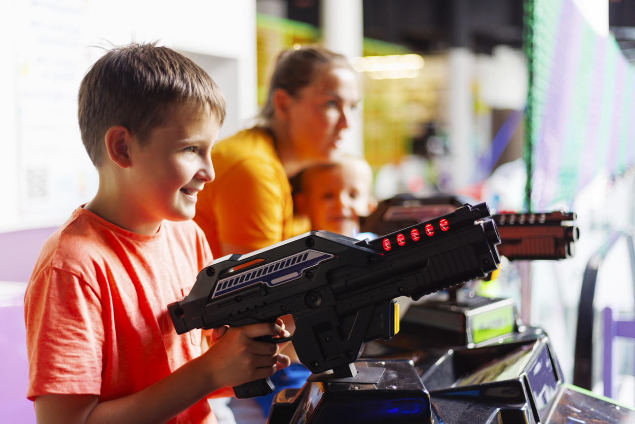 Boy playing arcade game with space like gun