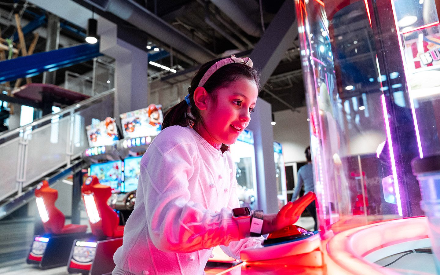 Girl playing an arcade game with glowing buttons.